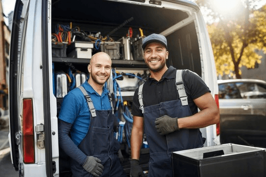 Two professional technicians smiling beside their equipped work van